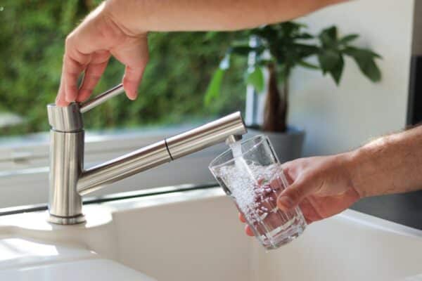 Klares Wasser wird aus einem Küchenhahn in ein Glas eingeschenkt – Wasserfilter Test 2026